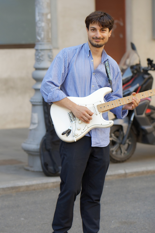 25 - Young man holding a white Fender Stratocaster-style electric guitar